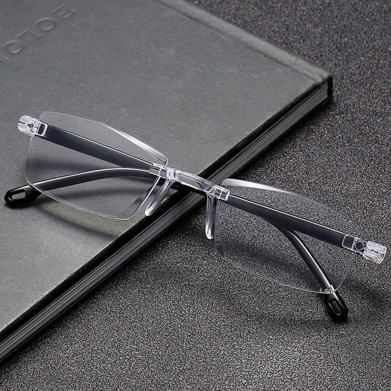 Clear rimless eyeglasses on a dark surface with a notebook